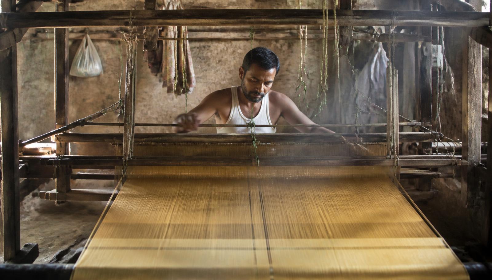 Indian handloom artisan weaving Kosa silk at a wooden loom
