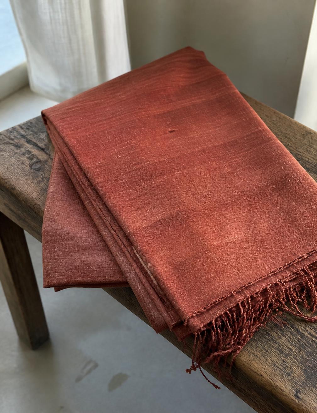 Natural undyed tussar dupatta hanging against a plaster wall